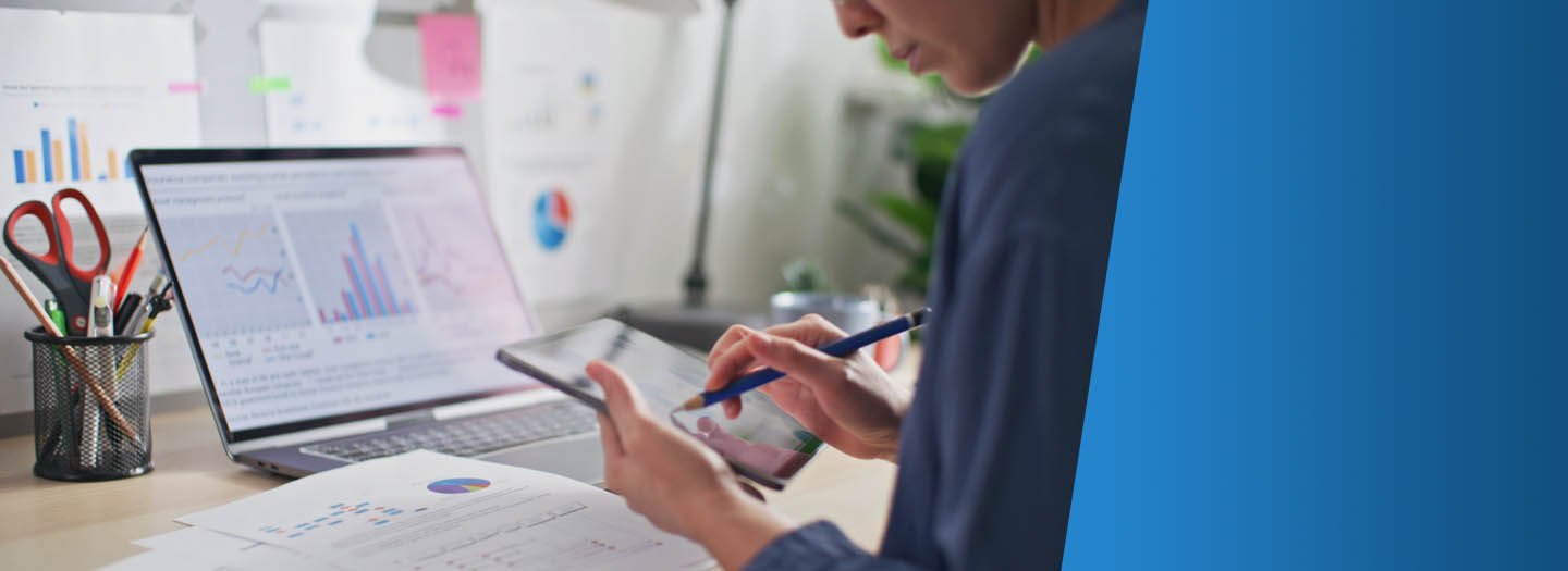Woman reviewing finances on computer and tablet